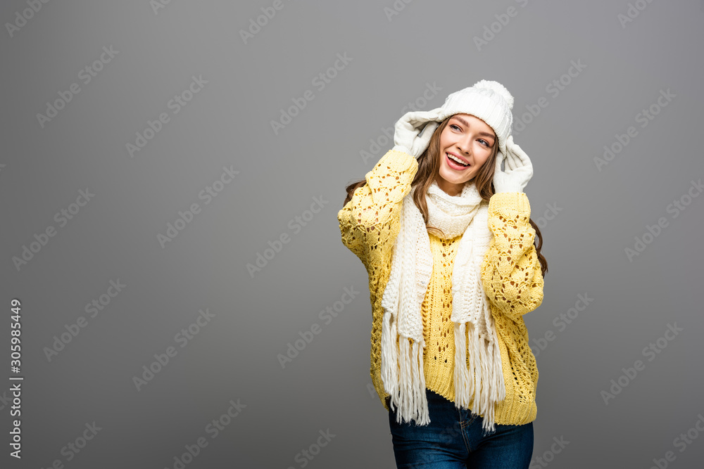 happy girl in yellow sweater, scarf, hat and gloves on grey