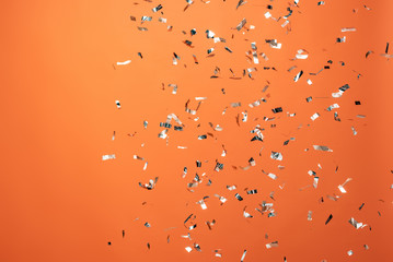 shiny silver confetti on orange background
