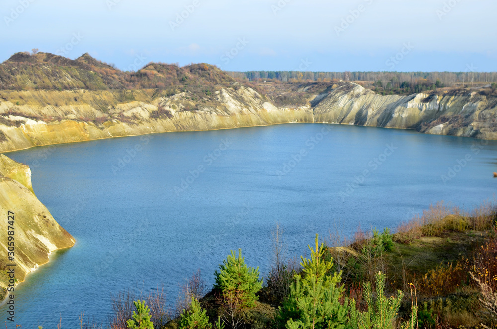 Artificial lake was is formed after the extraction of chalk in an industrial quarry at Krasnoselsky village in the Belarus. Water in open pit between the mountains. Belarusian Maldives
