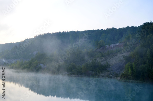 Morning mood with sunrise with a haze over a lake in the mountains. That artificial lake formed after the extraction of chalk in an industrial quarry at Krasnoselsky village in the Belarus. © MaxSafaniuk