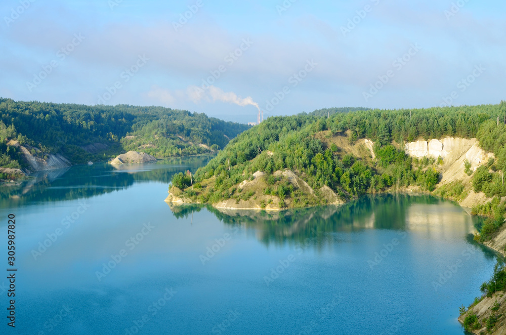Artificial lake was is formed after the extraction of chalk in an industrial quarry at Krasnoselsky village in the Belarus. Turquoise background of the clear ocean water in summer tropical season. Artificial lake was is formed after the extraction of chalk in an industrial quarry at Krasnoselsky village in the Belarus. Turquoise background of the clear ocean water in summer tropical season.