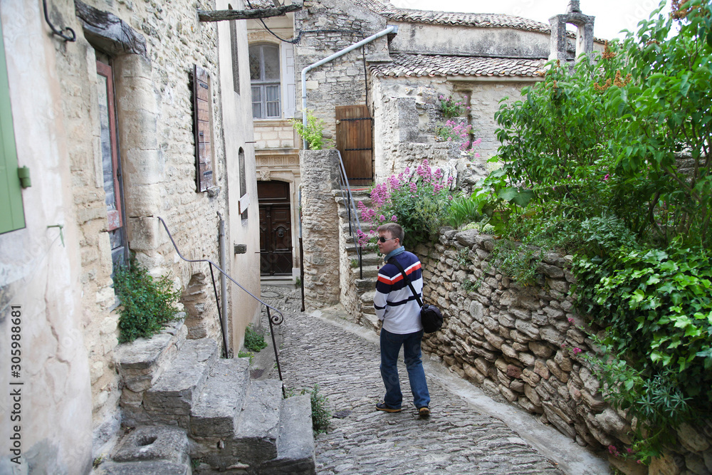 Young man in sunglasses walks on historical streets in small village in Provence