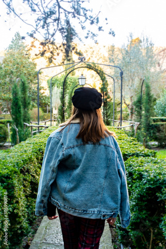 Backwards portrait, of a pretty young girl wearing a denim jacket and a black beret, in the gardens of the Valldemossa Charterhouse, Tramontana Majorcan area