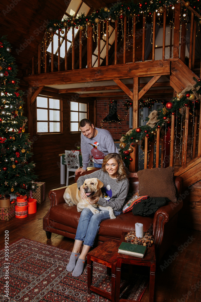 family on the couch with a dog. Christmas tree with presents