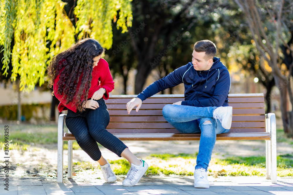 Fototapeta premium Young adult bothering girl on a park bench