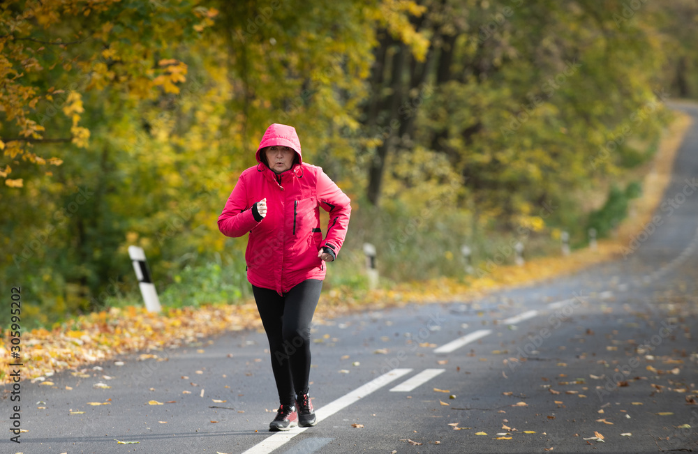 Middle age woman wearing sportswear and running in forest. Middle age woman wearing sportswear and running in forest.