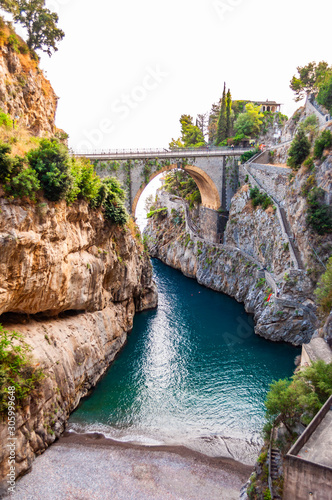 View on Fiordo di Furore arc bridge built between high rocky cliffs above the Tyrrhenian sea bay in Campania region. Unique cove under the cliffs, natural gorge, canyon or fiord
