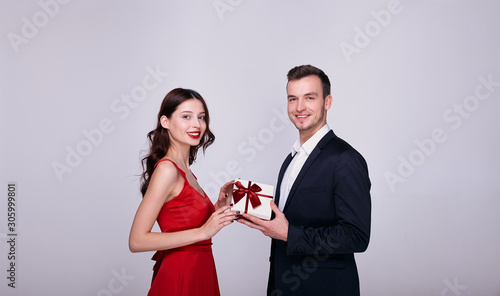 An elegant man in a suit gives a surprise to a woman, gives her a gift.