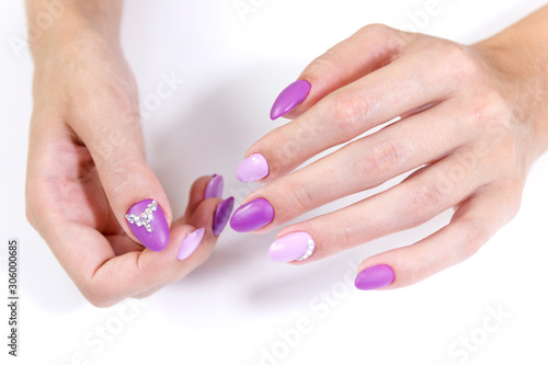 Hands of a client of a beauty salon with manicure gel varnish in two colors and rhinestones.