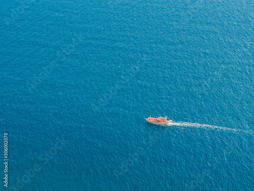 Small tourist boat is sailing in the blue sea. Top view. Copy space. Vacation background