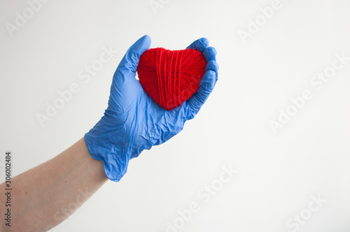 a hand in a blue glove holds a red heart. Medical concept. Copy space © vadim yerofeyev