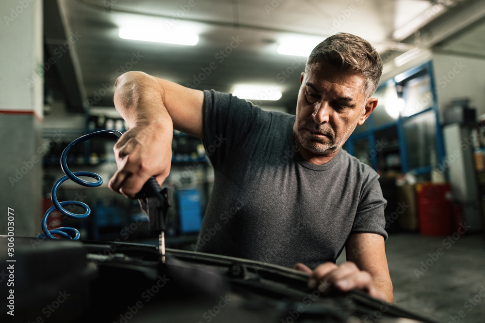 Auto mechanic working on car engine in a repair shop. Auto mechanic working on car engine in a repair shop.