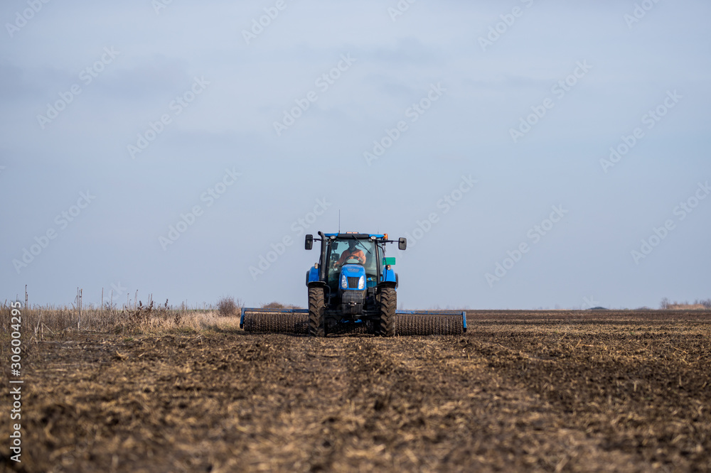 Fototapeta premium Tractor on the field cultivates the land.