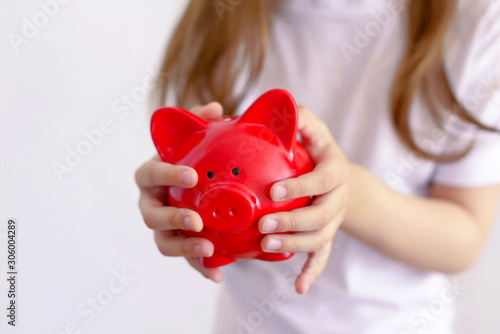 Young child girl in a Santa hat keeps a piggy Bank isolated.