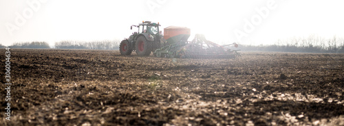 Fotografie Farmer with tractor seeding, sowing crops at agricultural fields
