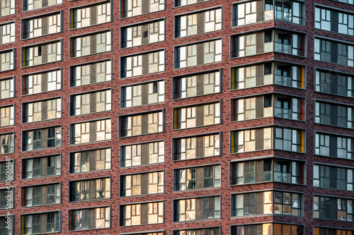 Brick facade of a residential multi-storey building with large windows. Modern architecture. Real estate in a big city. Background from the wall of the house.