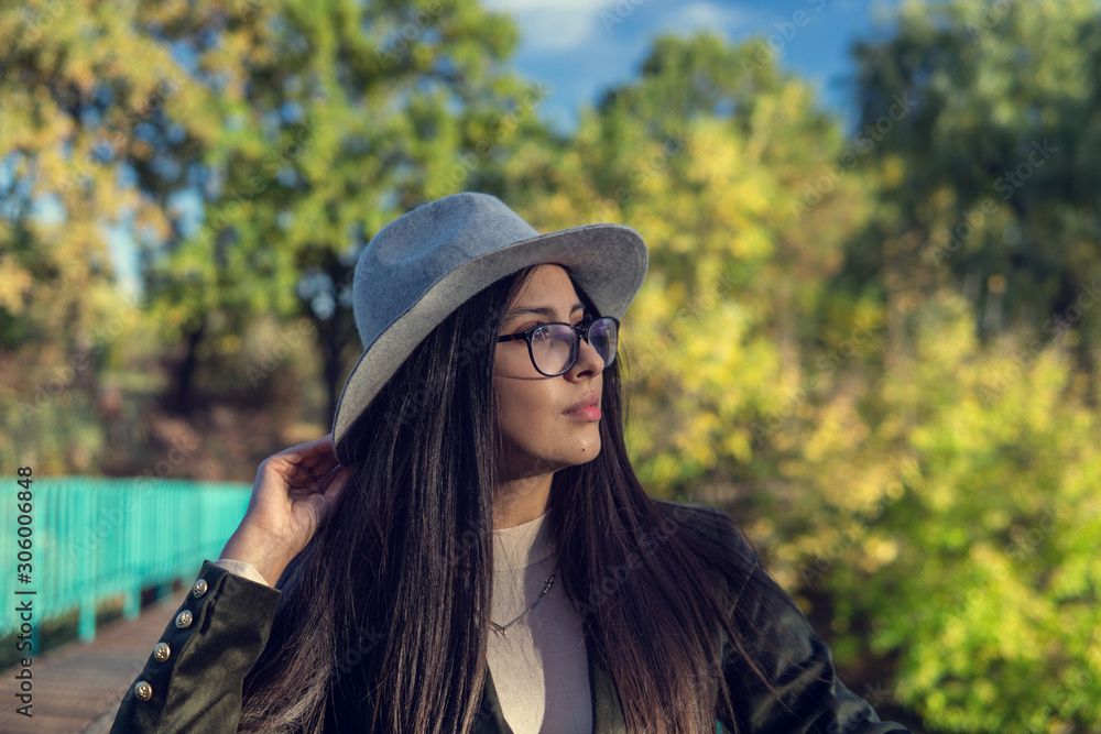 Close up of happy emotionally brunette woman with long hair and hat, smiling at camera. Beautiful model with perfect makeup after salon, posing in park. Concept of fashion and beauty. Close up of happy emotionally brunette woman with long hair and hat, smiling at camera. Beautiful model with perfect makeup after salon, posing in park. Concept of fashion and beauty.