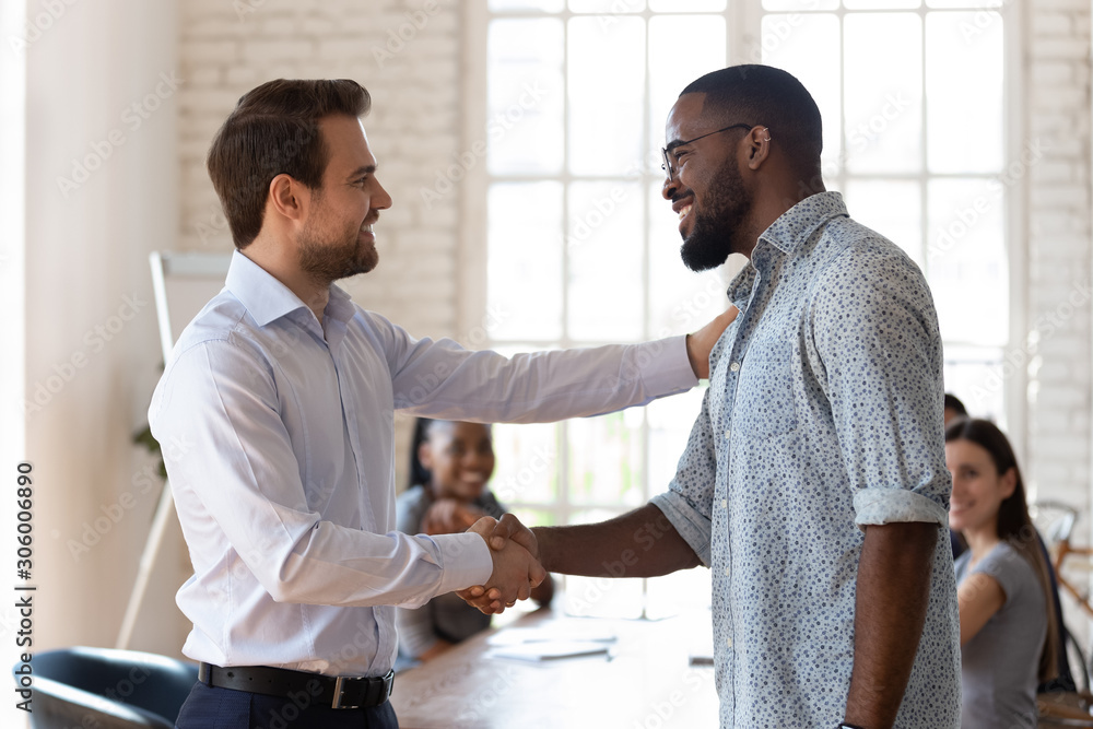 Obraz premium Confident company director shaking hands with happy african american employee.