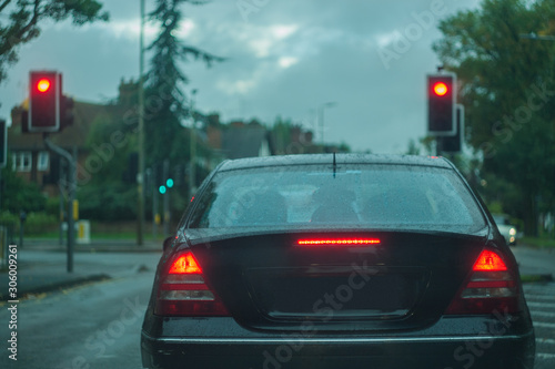 Rear view of a car, displaying stop ligths and red lights, traffic signals, at dusk, in poor visibility conditions. Concept photo, with shallow depth of field and toned colors.