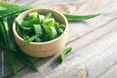 Slices of fresh juicy aloe vera stems in a wooden bowl on a wooden surface, closeup. Alternative medicine