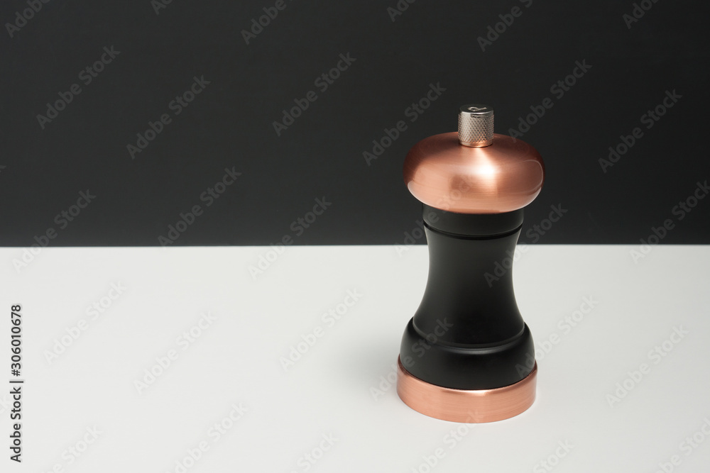 Black pepper mill with copper inserts on black & white background.