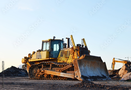 Track-type bulldozer, earth-moving equipment. Land clearing, grading, pool excavation, utility trenching, utility trenching and foundation digging during of large construction jobs.