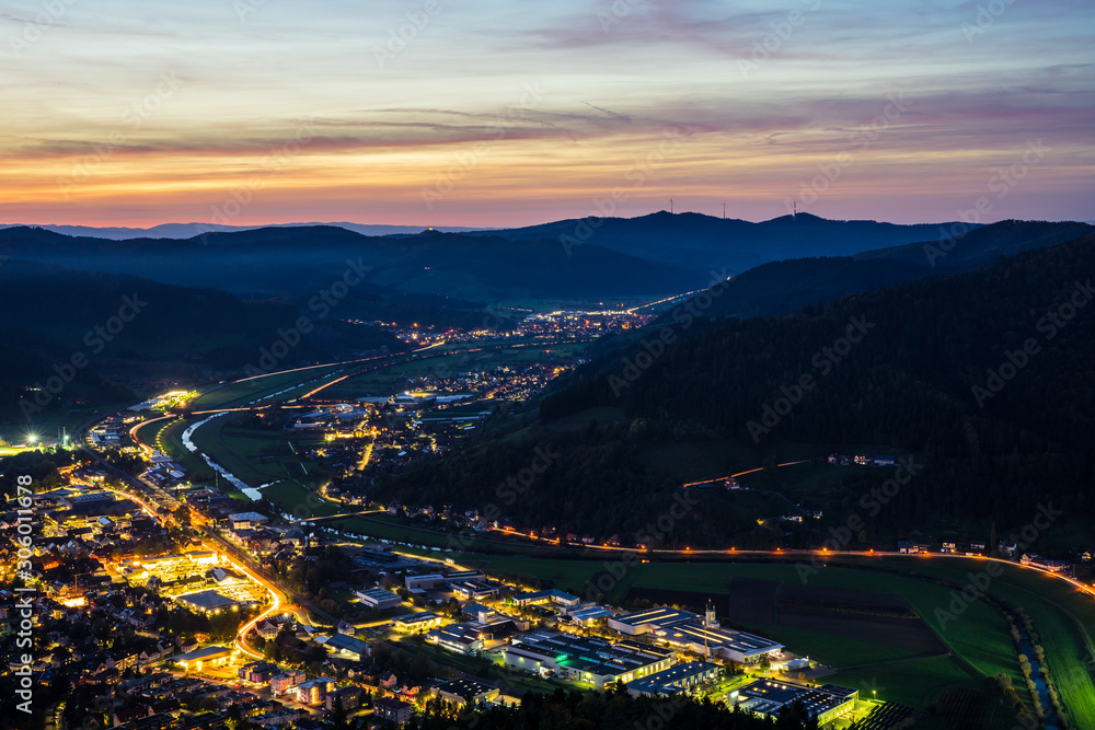 Obraz premium Germany, Black forest houses of city haslach im kinzigtal, streets and cityscape illuminated by night, aerial view from above with red sky, a perfect nature landscape surrounding the village