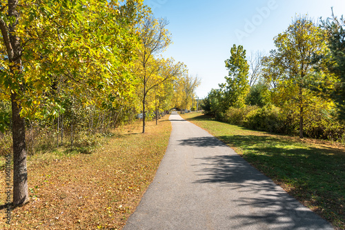 Empty paved path for pedestrains and cyclists lined with yellow trees on a clear autumn day. Keene, NH, USA. photo