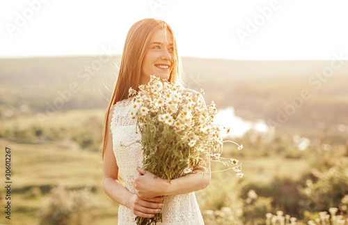 Fotografie Cheerful teenager with bunch of chamomiles in nature