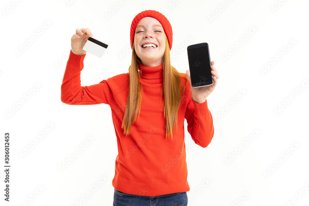 little girl in a red hat rejoices to the new phone holding a credit card in his hand on a white background little girl in a red hat rejoices to the new phone holding a credit card in his hand on a white background
