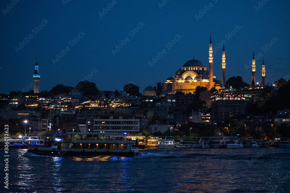 Istanbul, Turkey, Middle East: night skyline of the city with view of boats in the Golden Horn and the illuminated Suleymaniye mosque, Ottoman imperial mosque commissioned by Suleiman the Magnificent 