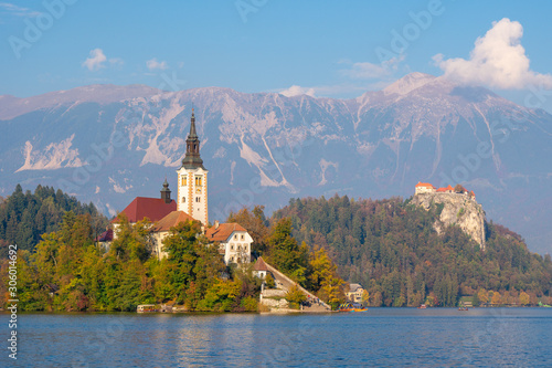 Beautiful church in middle of slovenian Bled lake surrounded by mountains on clear day with blue skies in Bled, Slovenia. Travel landmarks and landscapes concept