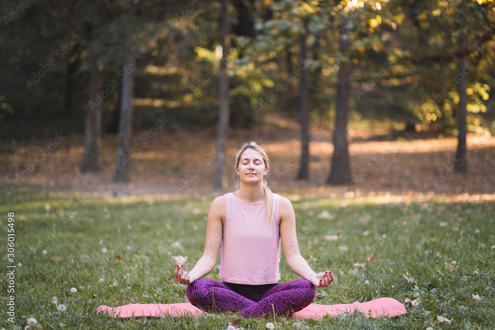 Young woman doing yoga in the park in autumn