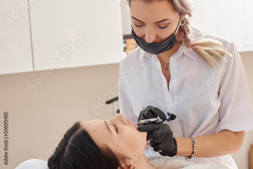 Close up of beautician expert's hands injecting botox in female forehead.Anti-aging, nourishing, vitamins treatment at spa salon. Aesthetic cosmetology.