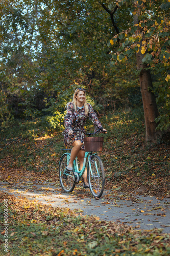 Young woman riding a bicycle in the park in autumn