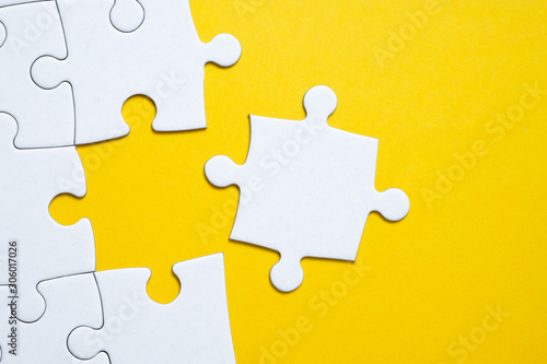 Final white piece is lying next to the jigsaw puzzle on yellow background.