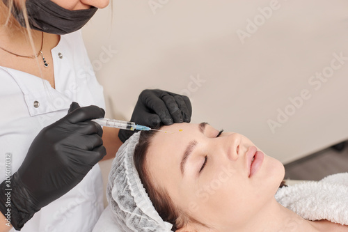 Woman gets injection in her face. Beauty woman giving beauty injections. Young woman gets beauty facial injections in the cosmetology salon. Face aging injection. Aesthetic Medicine  Cosmetology