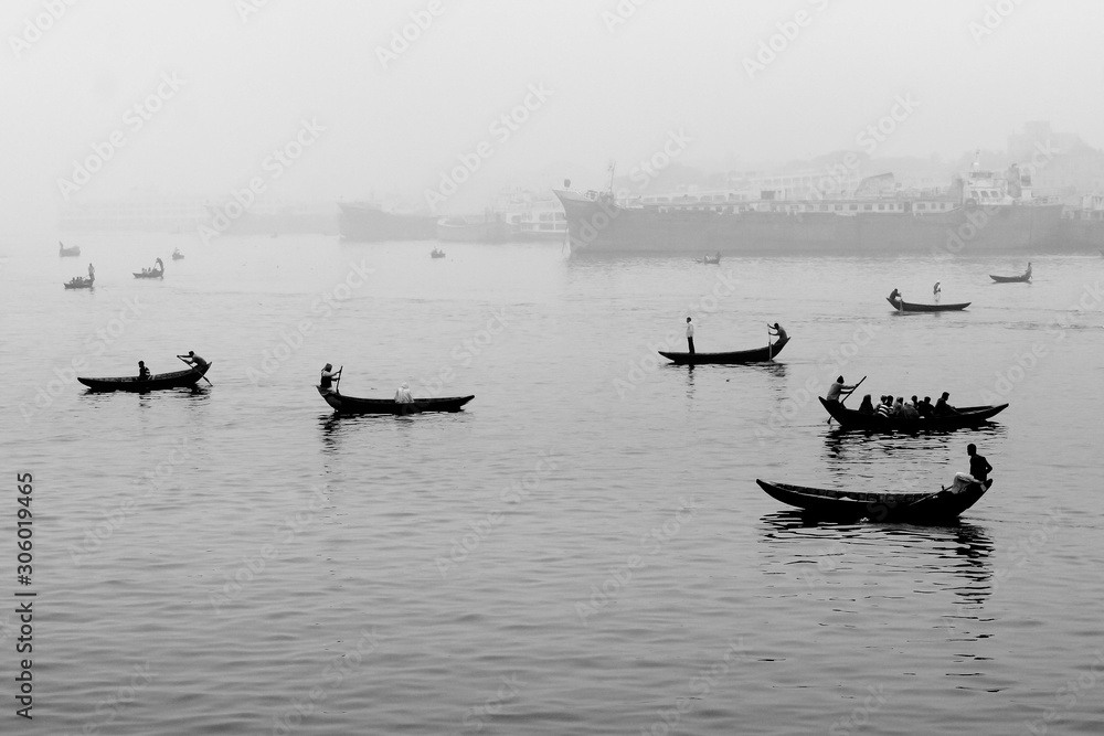 Bangladesh – January 06, 2014: In the midday afternoon, people are crossing the river by boat and this year the fog of the winter is engulfed in the river Buriganga.