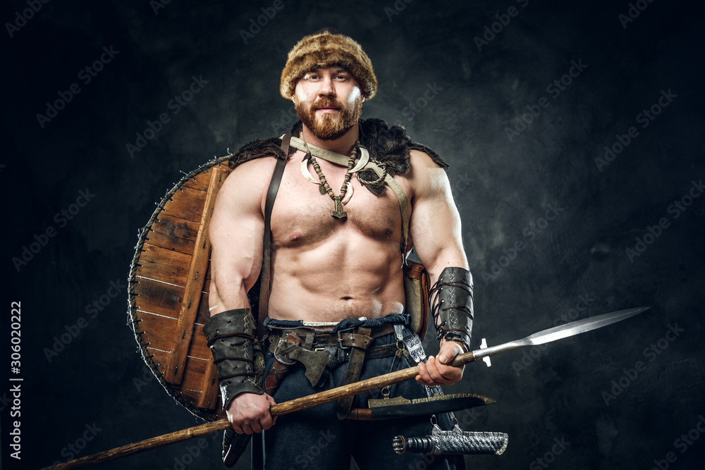 Severe barbarian in warrior clothes, posing on a dark background.