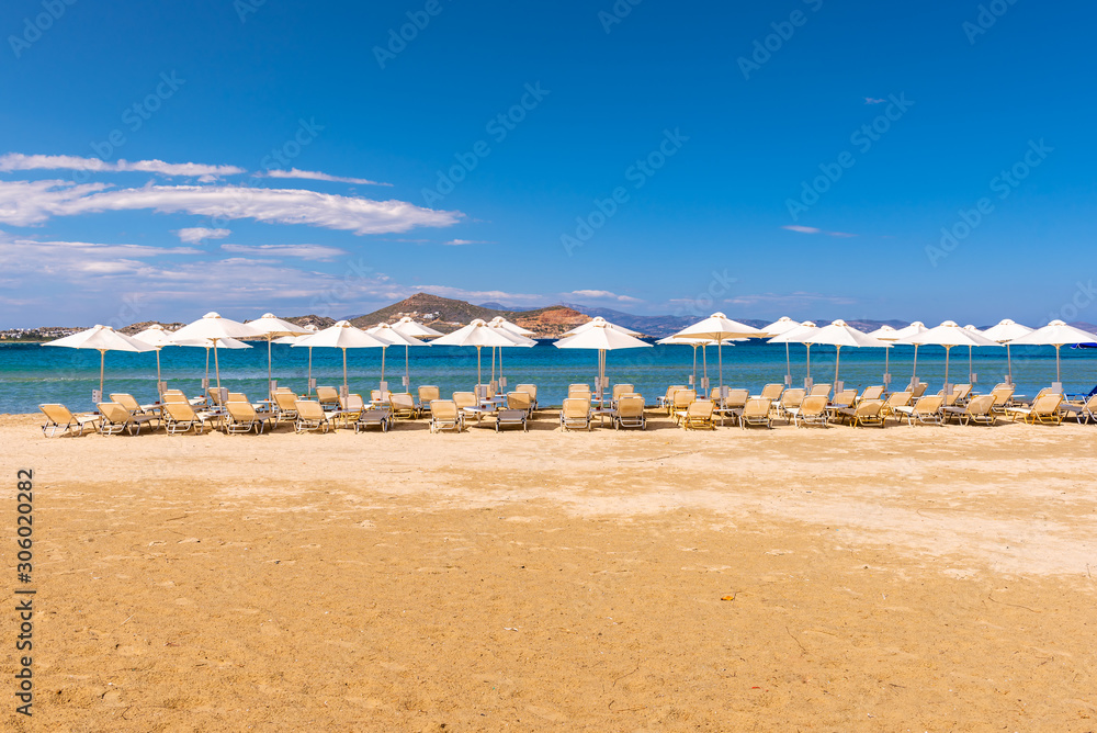 Sunbeds with umbrellas on Agios Georgios beach, very popular resort on Naxos island, Greece.