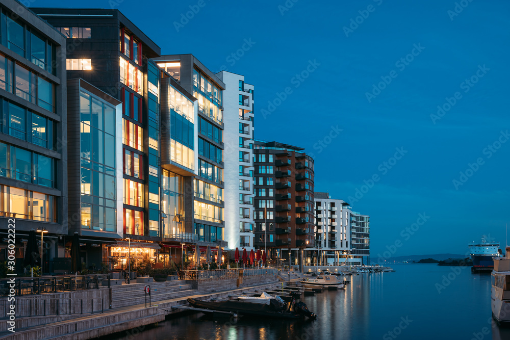 Oslo, Norway. Night View Embankment And Residential Multi-storey Houses In Aker Brygge District. Summer Evening. Residential Area Reflected In Sea Waters. Famous And Popular Place