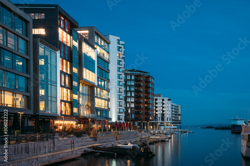 Oslo, Norway. Night View Embankment And Residential Multi-storey Houses In Aker Brygge District. Summer Evening. Residential Area Reflected In Sea Waters. Famous And Popular Place