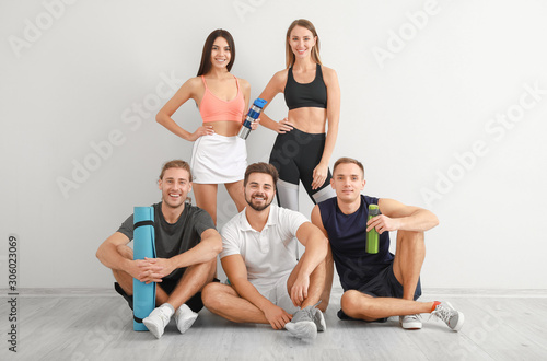 Group of sporty friends near white wall