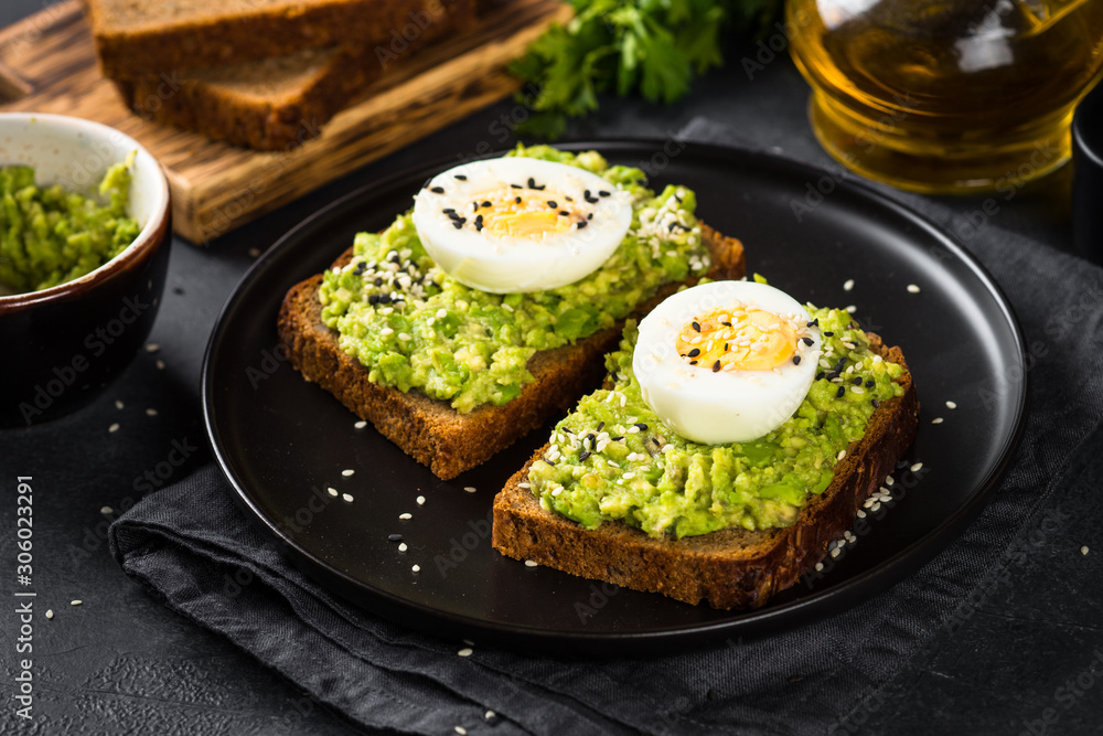 Avocado Sandwiches on black background.