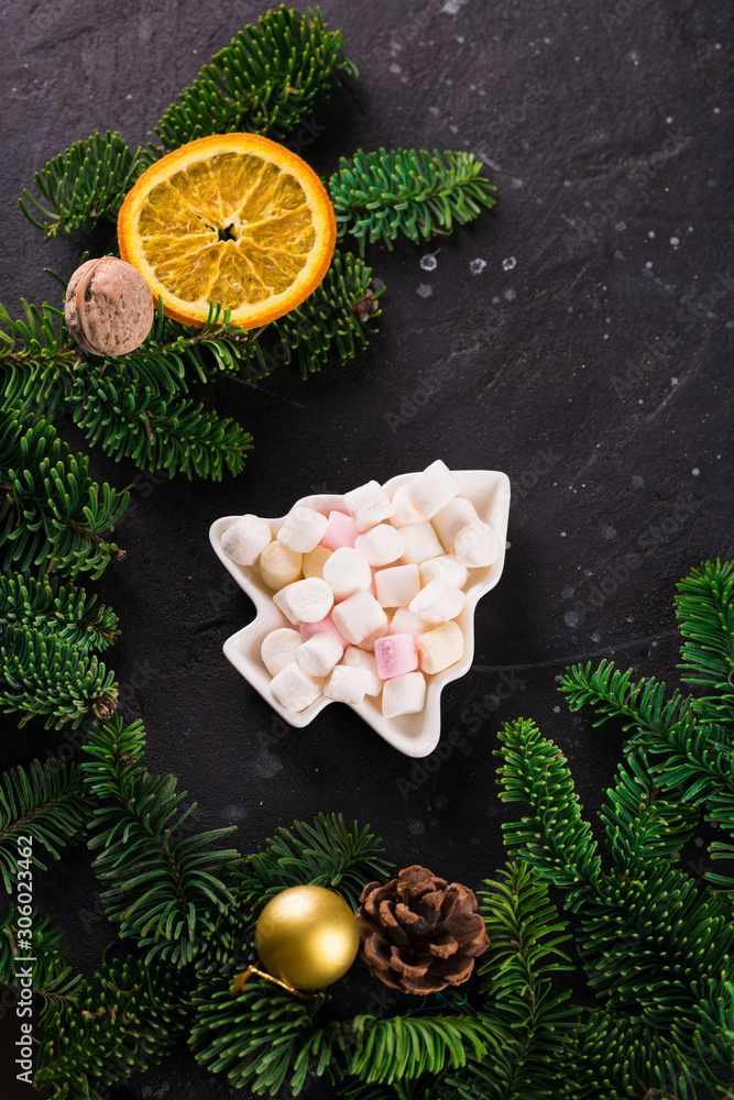 Marshmallows in Christmas tree shape plate on dark background with fir tree green branches. Smores for coffee or hot chocolate, copy space Marshmallows in Christmas tree shape plate on dark background with fir tree green branches. Smores for coffee or hot chocolate, copy space