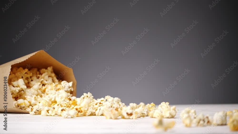 Popcorn in the paper bag on the table. Bag falls and pieces spills on the table . No people Popcorn in the paper bag on the table. Bag falls and pieces spills on the table . No people