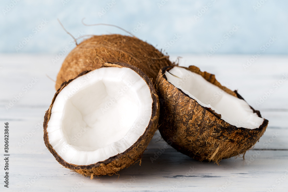Health content, whole coconut and split in half, on a light wooden table, Health content, whole coconut and split in half, on a light wooden table,