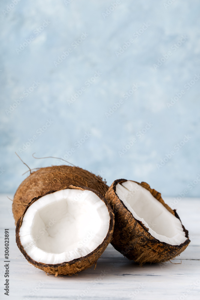 Health content, whole coconut and split in half, on a light wooden table, vertical Health content, whole coconut and split in half, on a light wooden table, vertical