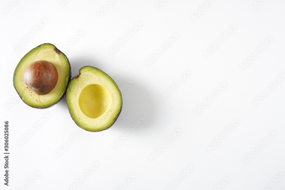 Two avocado halves on a white background with copy space