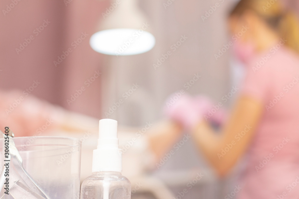 Close up of various professional cosmetics and oils, tools for pedicure on a white table. View from a distance of a specialist wearing gloves pedicuring for a client in an armchair. Beauty saloon Close up of various professional cosmetics and oils, tools for pedicure on a white table. View from a distance of a specialist wearing gloves pedicuring for a client in an armchair. Beauty saloon